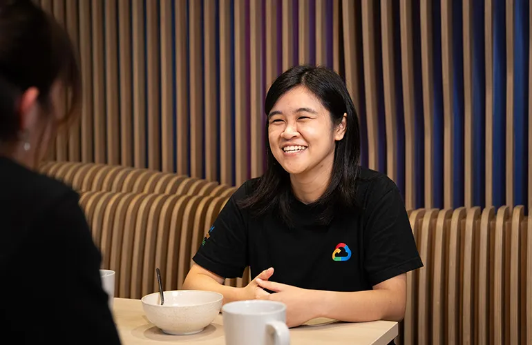 Wan Qi is laughing while chatting with her colleague.