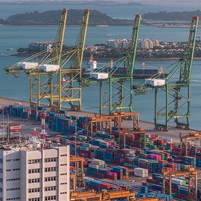 Aerial view of a major shipping port with cranes and stacked containers, symbolizing global trade, logistics, and economic connectivity.