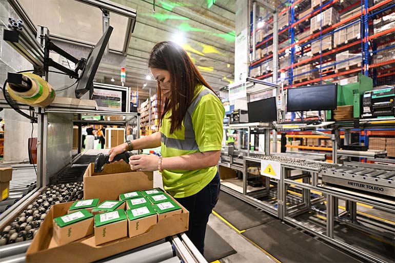A weight control station operator physically checking products against customers' orders at the packing workstation in Schneider Electric's new logistics distribution centre. Image courtesy of SPH Media.