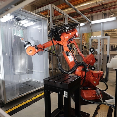 Industrial robotic arm operating in a factory setting, equipped with precision tools and surrounded by automated machinery for advanced manufacturing processes.
