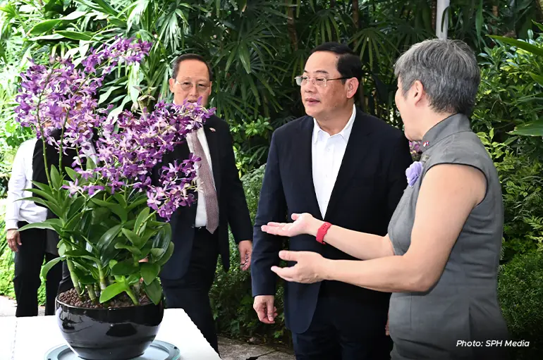 NParks chief executive officer Hwang Yu-Ning (right) showing the Dendrobium Sonexay Siphandone orchid hybrid to Lao Prime Minister Sonexay Siphandone (centre). With them is Manpower Minister Tan See Leng (left).