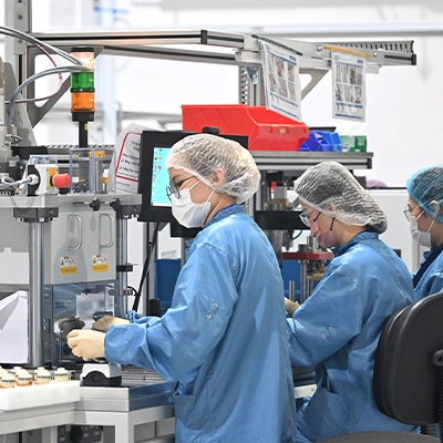Workers in cleanroom suits operate precision machinery in a high-tech manufacturing facility, emphasizing sterile and controlled conditions.
