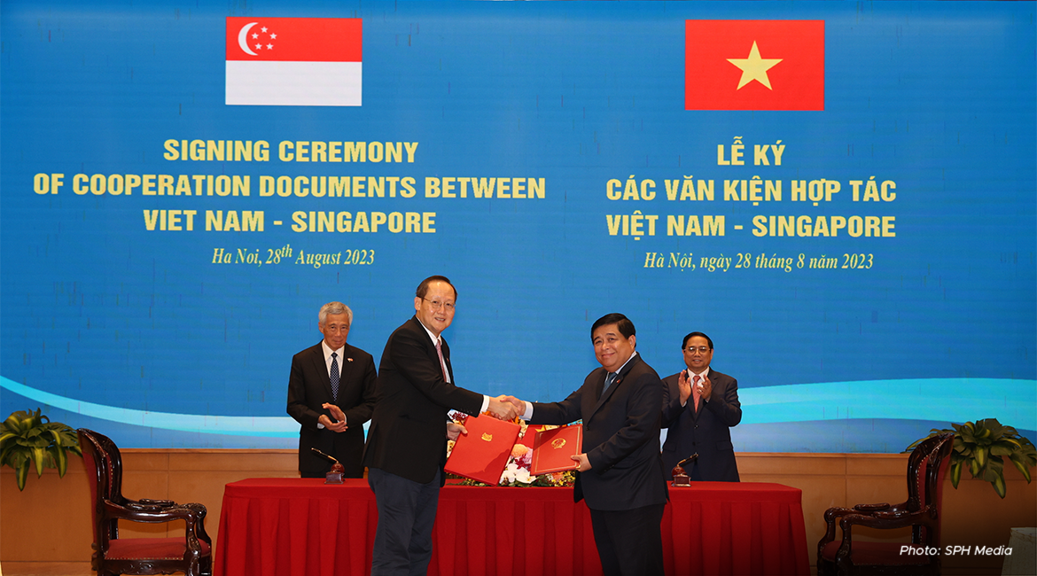 PM Lee Hsien Loong (in background, left) and Vietnam's PM Pham Minh Chinh (in background, right) witnessing the exchange of letters by Second Minister for Trade and Industry Tan See Leng and Vietnam’s Planning and Investment Minister Nguyen Chi Dzung on 28 August 2023.