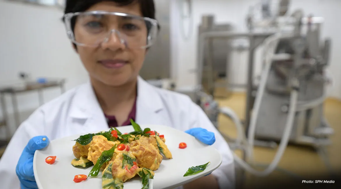 A scientist at FutureBites with a plate of salted egg CulinaPlant chunks.