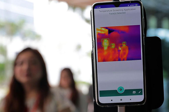 The real-time screening device, which uses a smartphone fitted with thermal and 3D laser cameras, detects the forehead temperature of individuals walking by, even if they are wearing spectacles, surgical masks or headgear. SOURCE: ST Photo, Gin Tay
